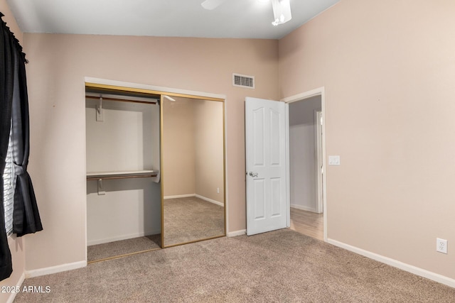 unfurnished bedroom with visible vents, a closet, carpet, baseboards, and vaulted ceiling