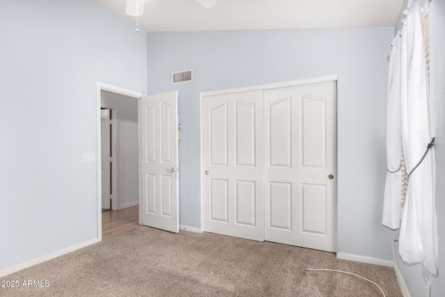 unfurnished bedroom with visible vents, baseboards, vaulted ceiling, carpet flooring, and a closet