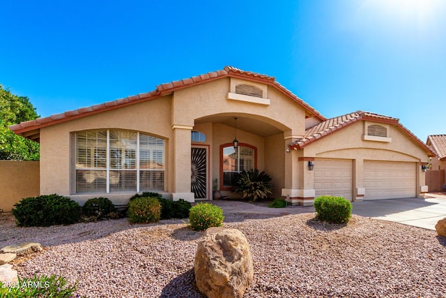 mediterranean / spanish-style home with stucco siding, an attached garage, and concrete driveway