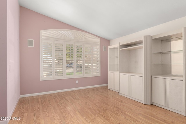 unfurnished bedroom featuring vaulted ceiling, light wood-style floors, baseboards, and visible vents