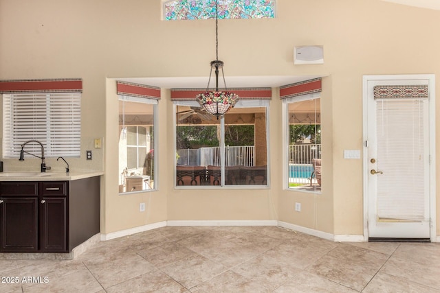 unfurnished dining area featuring light tile patterned flooring, baseboards, and a sink