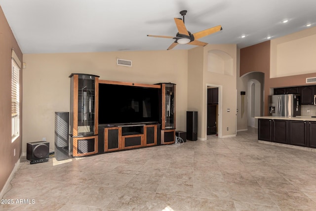 living area featuring visible vents, arched walkways, baseboards, and a ceiling fan