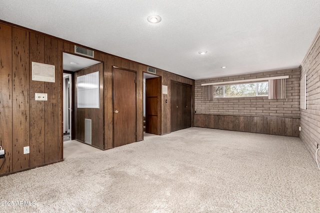 spare room featuring carpet floors and brick wall