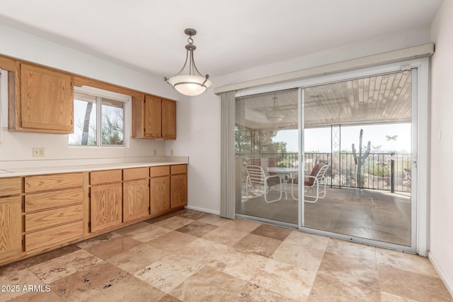 kitchen featuring brown cabinets, light countertops, hanging light fixtures, and baseboards