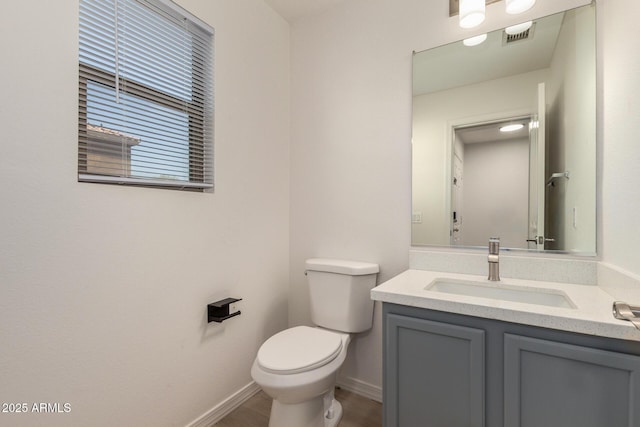 half bathroom featuring baseboards, visible vents, vanity, and toilet