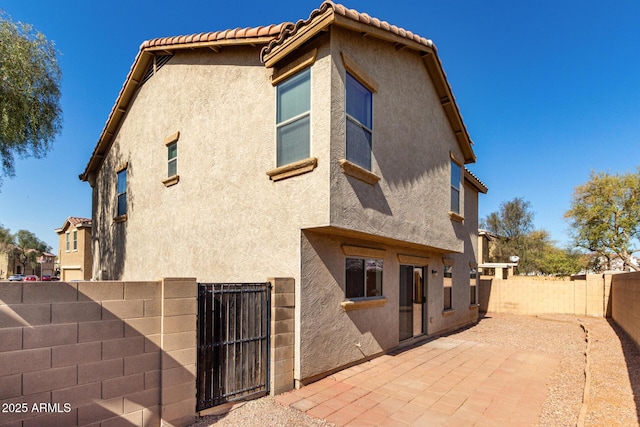 rear view of property with a patio area, a fenced backyard, a tiled roof, and stucco siding