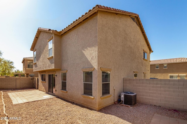 rear view of property featuring a patio, central AC unit, a fenced backyard, a tile roof, and stucco siding