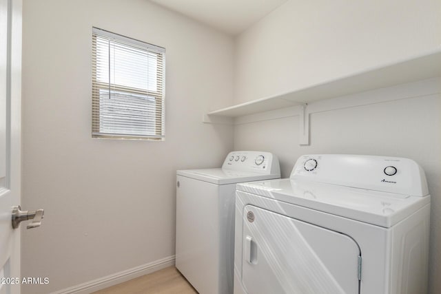 clothes washing area with light wood-style flooring, laundry area, washer and clothes dryer, and baseboards