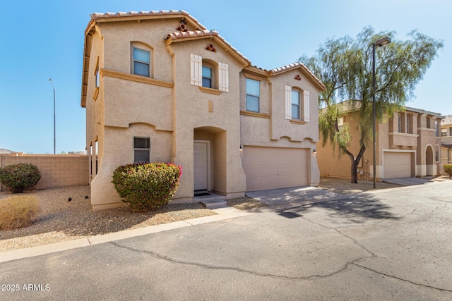 mediterranean / spanish-style house with stucco siding, concrete driveway, an attached garage, fence, and a tiled roof