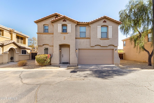 mediterranean / spanish home with a garage, driveway, a tiled roof, and stucco siding