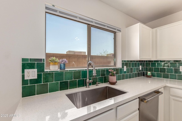 kitchen with white cabinetry, a sink, backsplash, and light stone countertops