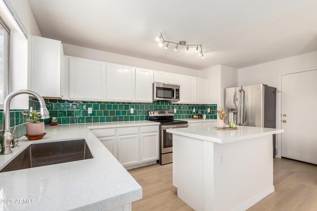 kitchen with light wood-style flooring, appliances with stainless steel finishes, decorative backsplash, and a sink