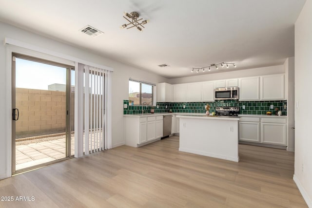 kitchen with appliances with stainless steel finishes, light wood-type flooring, visible vents, and white cabinets