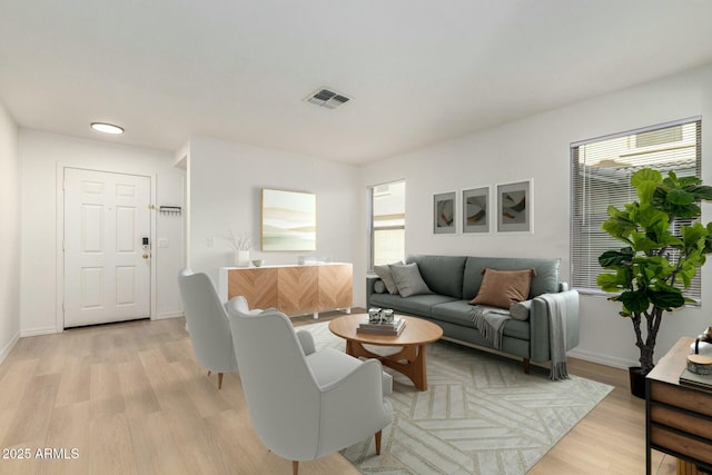 living area featuring baseboards, visible vents, and light wood-style floors