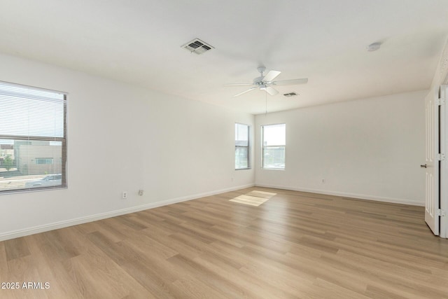 unfurnished room with light wood finished floors, baseboards, visible vents, and a ceiling fan