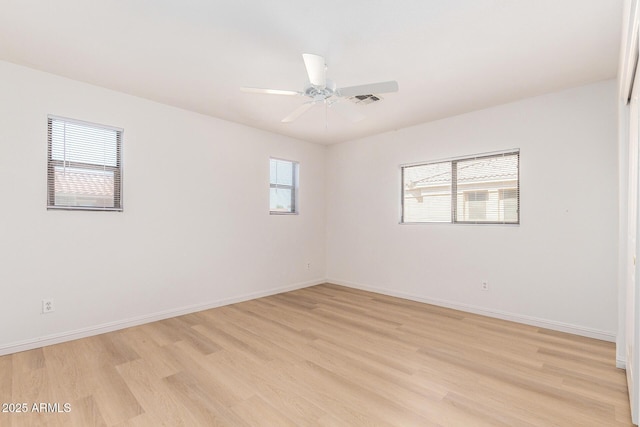 spare room with light wood-style floors, baseboards, visible vents, and a ceiling fan