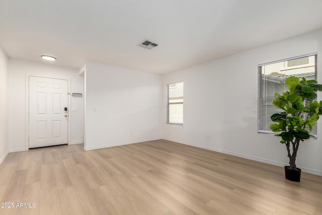 unfurnished room featuring light wood-type flooring, visible vents, and baseboards