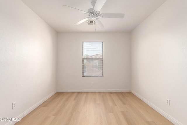 empty room featuring light wood finished floors, ceiling fan, visible vents, and baseboards