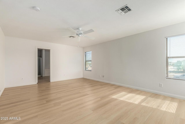 spare room featuring light wood-style floors, a wealth of natural light, visible vents, and a ceiling fan