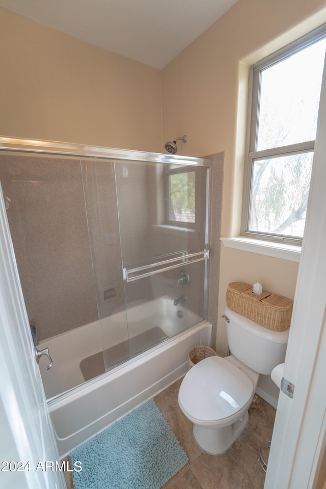 bathroom with tile patterned flooring, enclosed tub / shower combo, and toilet