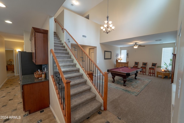 stairway featuring ceiling fan with notable chandelier, a high ceiling, tile patterned flooring, and billiards