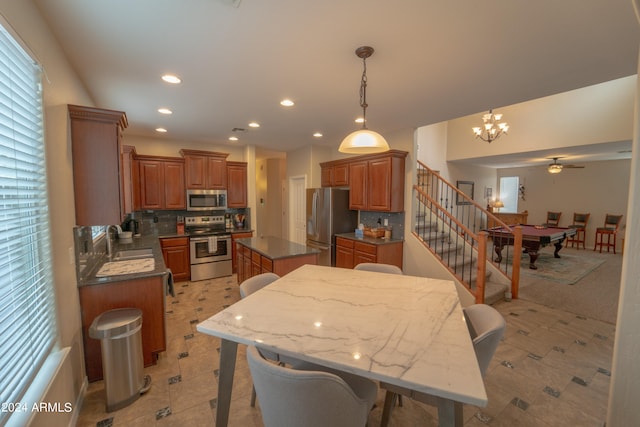 kitchen with appliances with stainless steel finishes, sink, decorative backsplash, and a center island