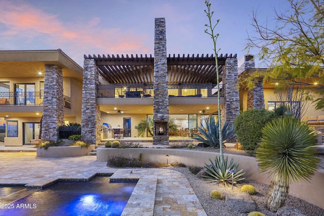 36389 N 105th Pl, Scottsdale, AZ 85262 - back of property at dusk with a balcony, stucco siding, a patio, and an outdoor pool