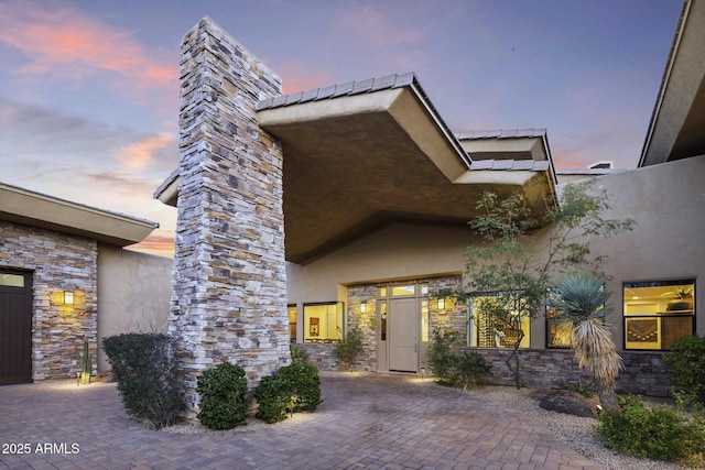 36389 N 105th Pl, Scottsdale, AZ 85262 - exterior entry at dusk featuring stucco siding, stone siding, and a chimney