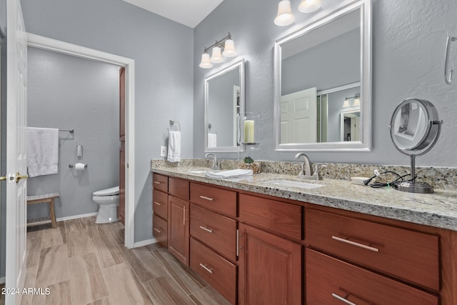 bathroom with dual sinks, toilet, and large vanity