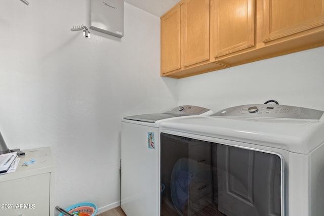 clothes washing area featuring independent washer and dryer and cabinets