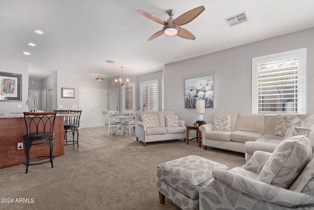 carpeted living room with ceiling fan with notable chandelier