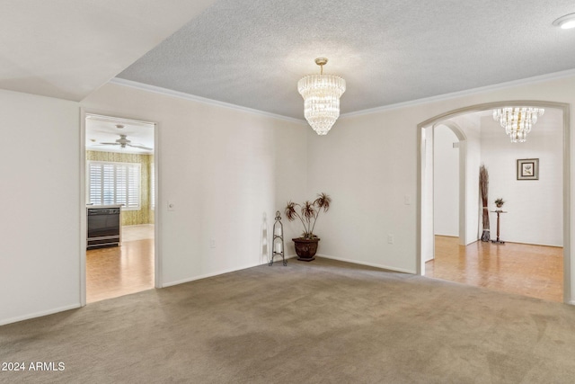 carpeted empty room featuring ceiling fan with notable chandelier, a textured ceiling, and ornamental molding