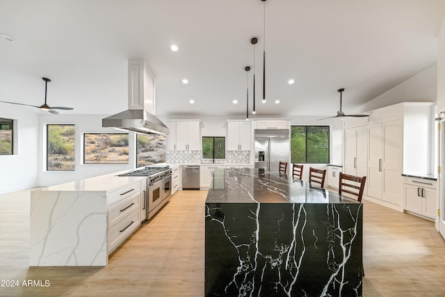 kitchen with wall chimney range hood, ceiling fan, premium appliances, and white cabinetry