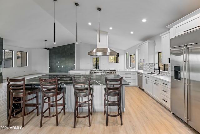 kitchen with lofted ceiling, a kitchen island, stainless steel appliances, and white cabinetry