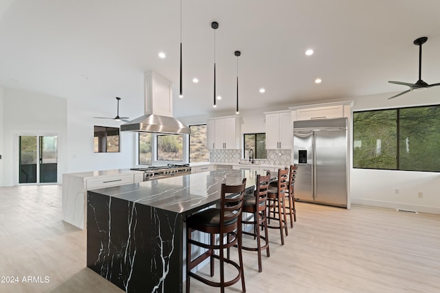 kitchen with a healthy amount of sunlight, white cabinetry, stainless steel appliances, a center island, and ceiling fan