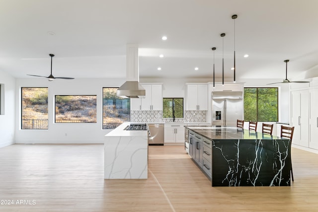 kitchen with white cabinetry, stainless steel appliances, light stone counters, a kitchen island, and ceiling fan