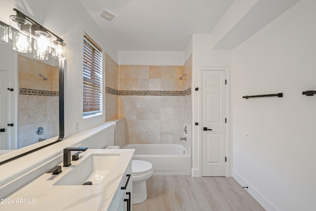 full bathroom featuring vanity, toilet, tiled shower / bath combo, and hardwood / wood-style floors