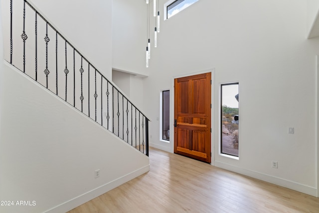 foyer entrance featuring a towering ceiling and light hardwood / wood-style flooring