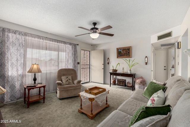 living area with a ceiling fan, visible vents, carpet floors, and a textured ceiling