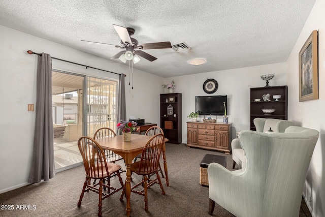 carpeted dining space featuring visible vents, a textured ceiling, and a ceiling fan