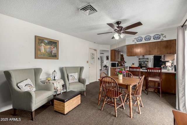 dining area featuring visible vents, light colored carpet, a textured ceiling, and ceiling fan