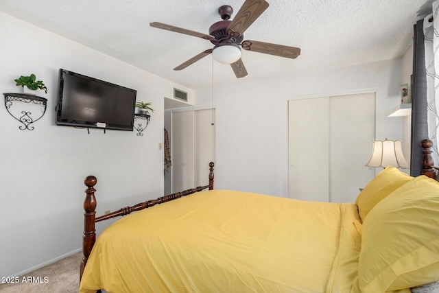 carpeted bedroom featuring visible vents, a ceiling fan, a textured ceiling, a closet, and baseboards