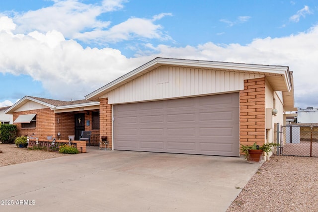 single story home with a gate, fence, concrete driveway, an attached garage, and brick siding