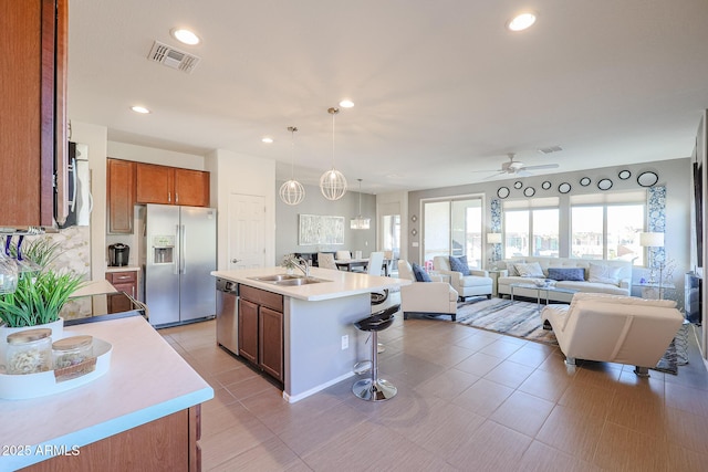 kitchen featuring an island with sink, ceiling fan, stainless steel appliances, a breakfast bar, and sink