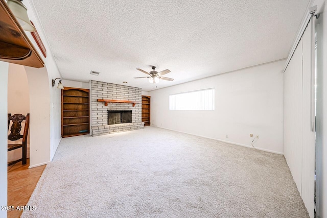 519 N Redondo Dr N, Litchfield Park, AZ 85340 - unfurnished living room featuring ceiling fan, a textured ceiling, light carpet, a brick fireplace, and arched walkways