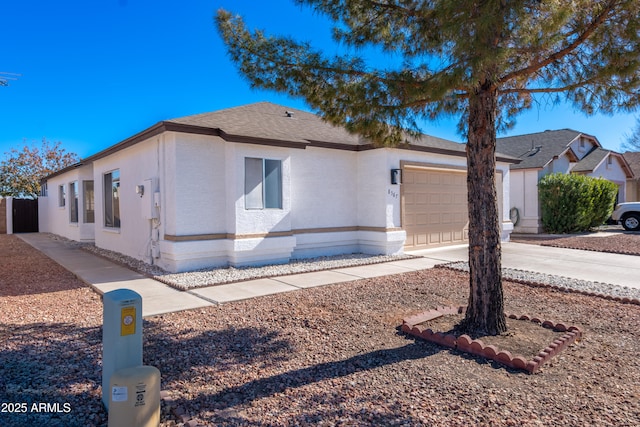 view of front of home with concrete driveway, an attached garage, and stucco siding