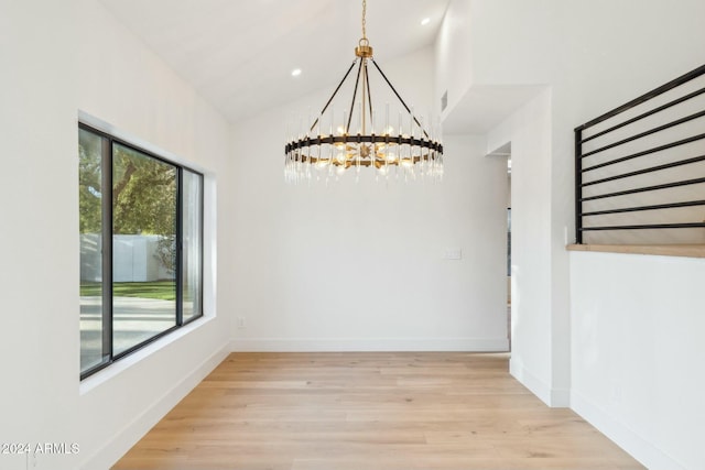 unfurnished dining area with light wood-type flooring, an inviting chandelier, and lofted ceiling