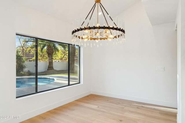 unfurnished dining area with hardwood / wood-style floors, plenty of natural light, and a notable chandelier