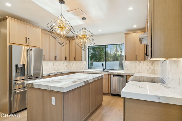 kitchen featuring appliances with stainless steel finishes, light brown cabinets, decorative light fixtures, and a kitchen island