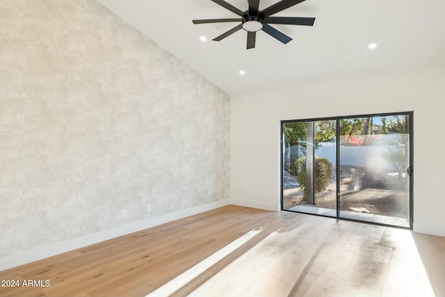 empty room with ceiling fan, vaulted ceiling, and light hardwood / wood-style flooring